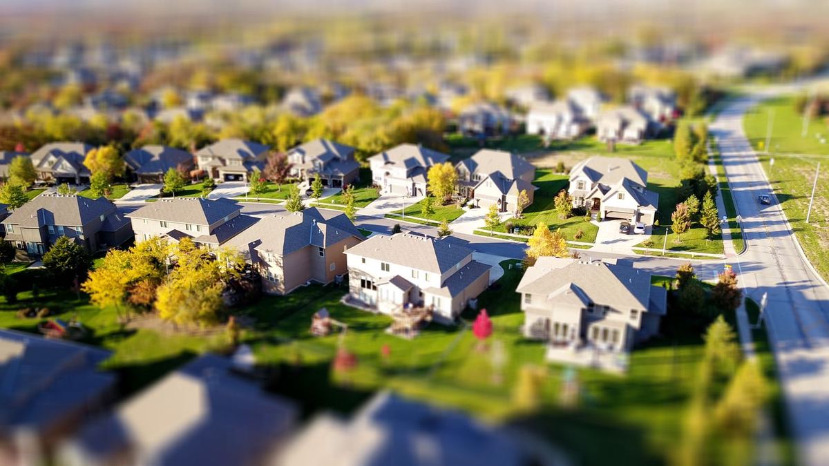 Aerial view of a suburban neighborhood of detached single-story homes on curving streets, with lawns and mature trees