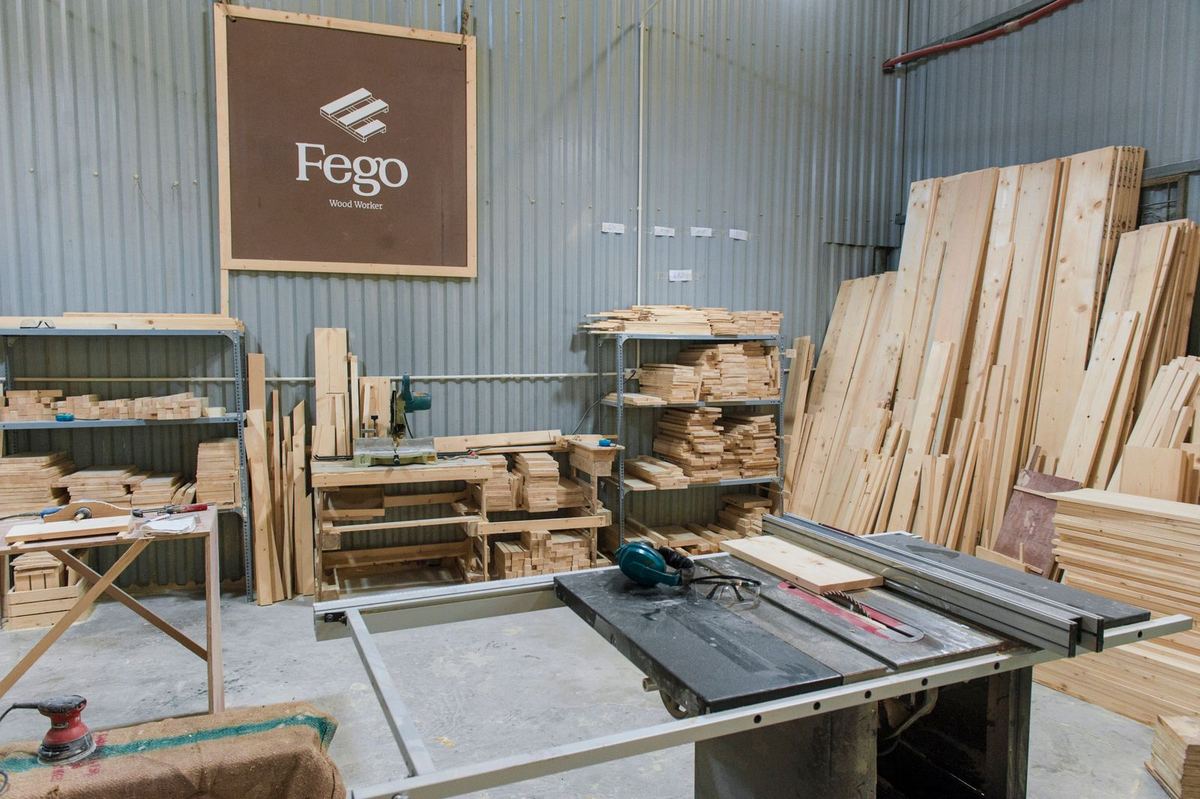 A pottery studio with wheels, stools and shelves of finished ware